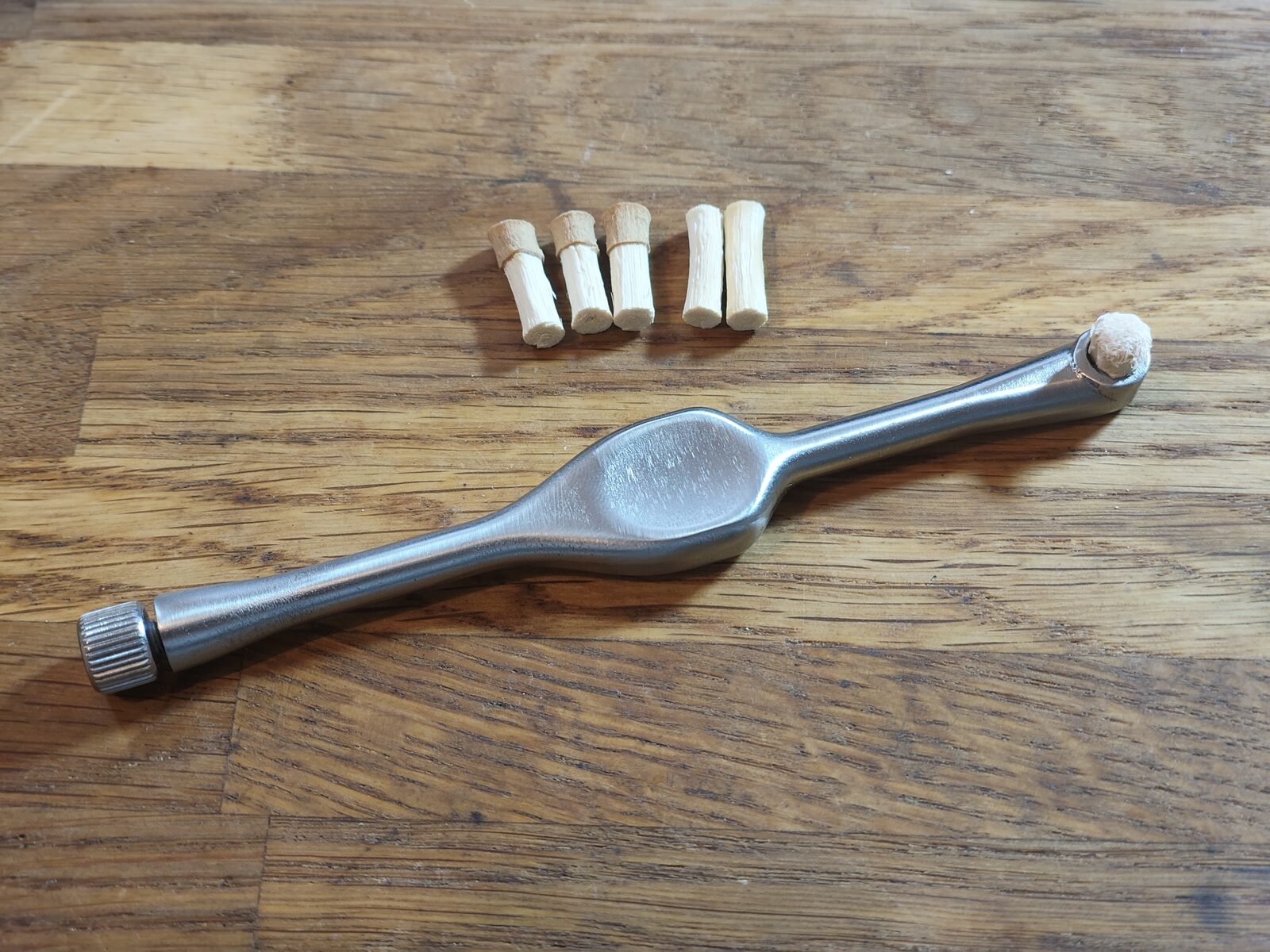 Der Griff mit einer ausgefransten Miswak-Spitze im Klemmkopf, daneben liegen Ersatzspitzen.